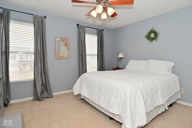 bedroom featuring a ceiling fan, light carpet, a textured ceiling, and baseboards