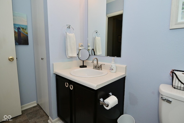 half bath featuring vanity, toilet, and baseboards