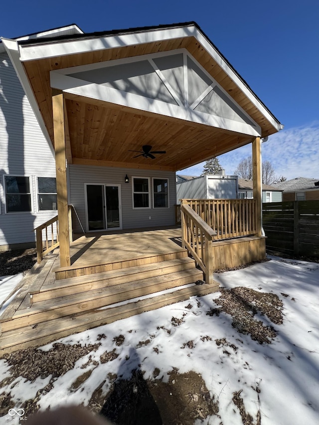 snow covered deck with ceiling fan and fence