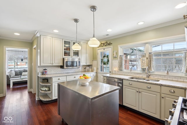 kitchen featuring a kitchen island, a sink, appliances with stainless steel finishes, glass insert cabinets, and pendant lighting