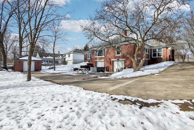 exterior space with a garage, a residential view, brick siding, and a chimney