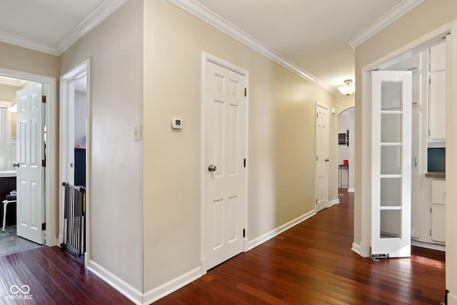 hall featuring arched walkways, ornamental molding, dark wood finished floors, and baseboards