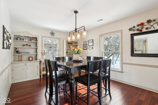 dining space with dark wood-style floors, visible vents, and baseboards