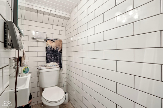 half bathroom featuring tile walls and toilet