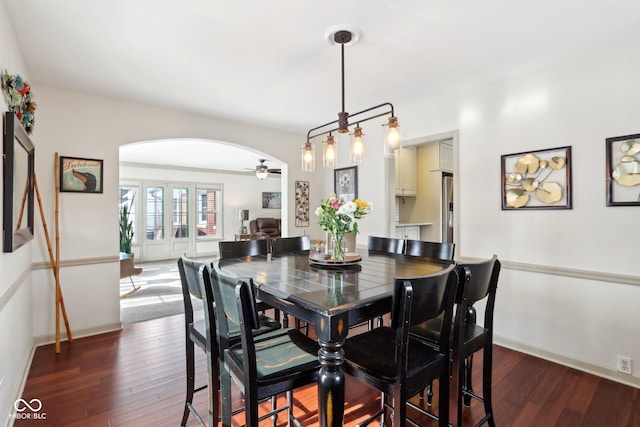 dining area with ceiling fan, baseboards, arched walkways, and dark wood finished floors