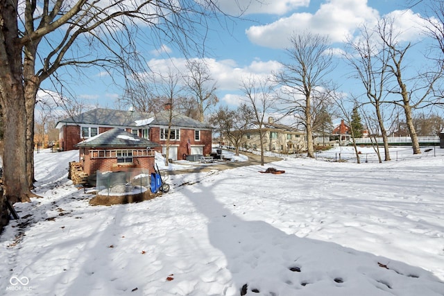 snow covered rear of property with brick siding and a residential view