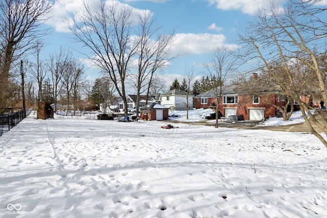 yard layered in snow featuring a residential view and a detached garage