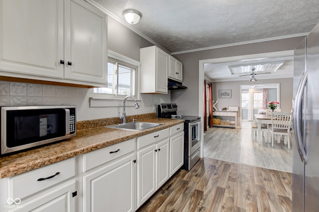 kitchen featuring dark wood-style floors, crown molding, appliances with stainless steel finishes, white cabinets, and a sink