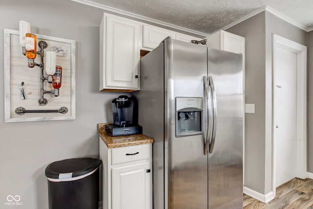 kitchen with white cabinets, light wood-style flooring, stainless steel refrigerator with ice dispenser, and a textured ceiling