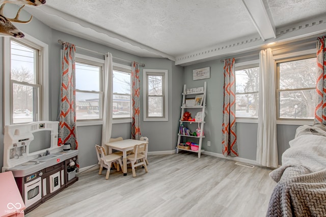 playroom featuring a textured ceiling, plenty of natural light, and light wood-style flooring