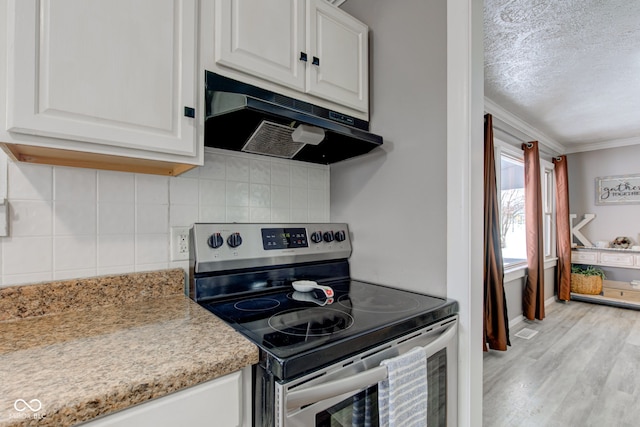 kitchen featuring ornamental molding, stainless steel range with electric cooktop, under cabinet range hood, white cabinetry, and backsplash