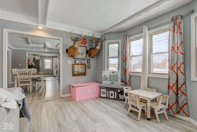 rec room with a textured ceiling, baseboards, and light wood-style floors