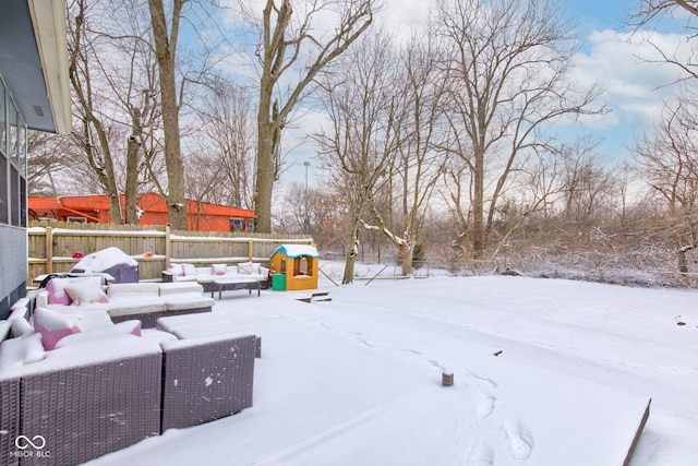 yard layered in snow featuring fence and a playground