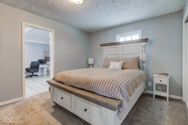 bedroom with baseboards, a textured ceiling, and light colored carpet