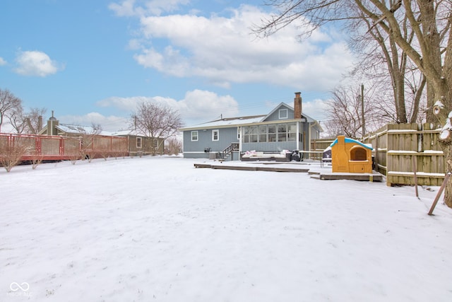 snow covered back of property with a chimney and fence