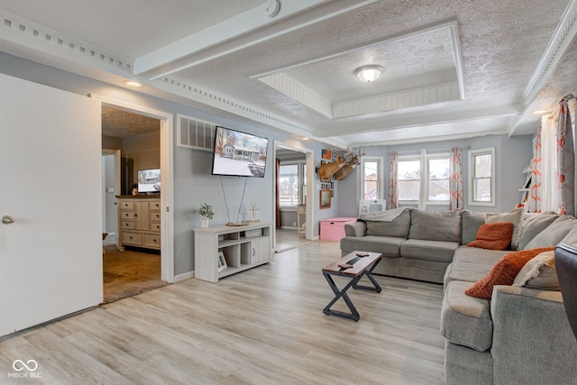 living room with a textured ceiling, visible vents, a raised ceiling, and light wood-style flooring