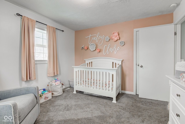 bedroom with a textured ceiling, a crib, baseboards, and light colored carpet