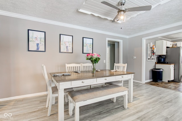 dining area with a textured ceiling, light wood-type flooring, and crown molding