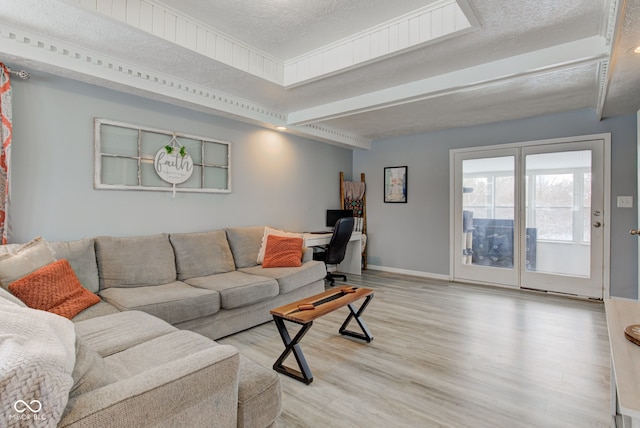 living room featuring light wood-style floors, a textured ceiling, and baseboards