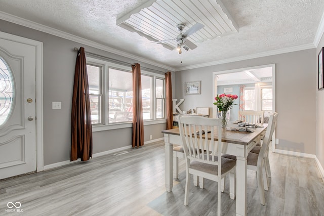 dining room featuring light wood finished floors, a ceiling fan, ornamental molding, a textured ceiling, and baseboards