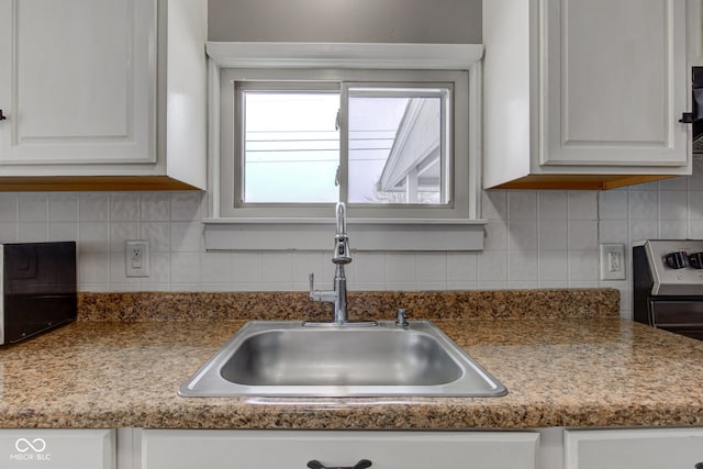 kitchen featuring tasteful backsplash, a sink, and white cabinets