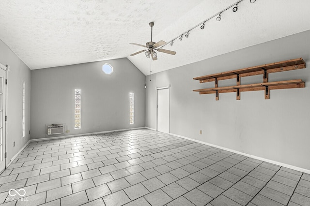 unfurnished room featuring a textured ceiling, a wall unit AC, a ceiling fan, vaulted ceiling, and tile patterned floors