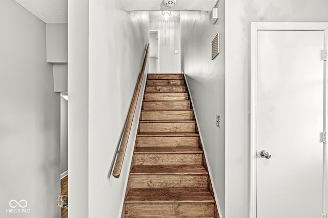 stairs featuring baseboards and a textured ceiling