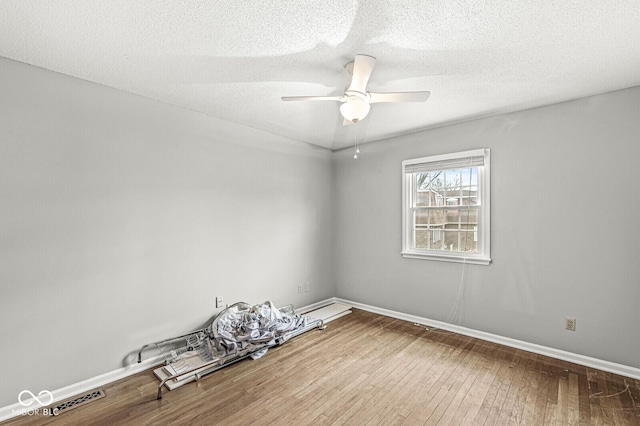 unfurnished room featuring a ceiling fan, wood-type flooring, a textured ceiling, and baseboards