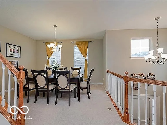 dining room featuring light carpet, a notable chandelier, baseboards, and stairs