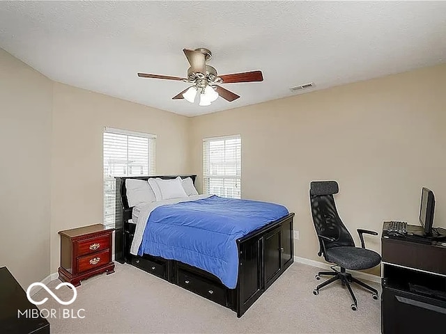 bedroom with baseboards, visible vents, a ceiling fan, and light colored carpet