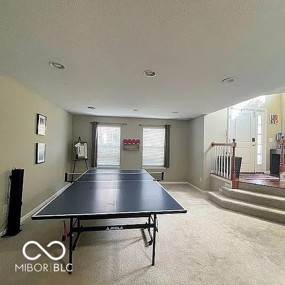 game room with carpet floors, baseboards, and a textured ceiling