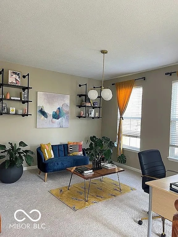 carpeted living room with a textured ceiling and baseboards