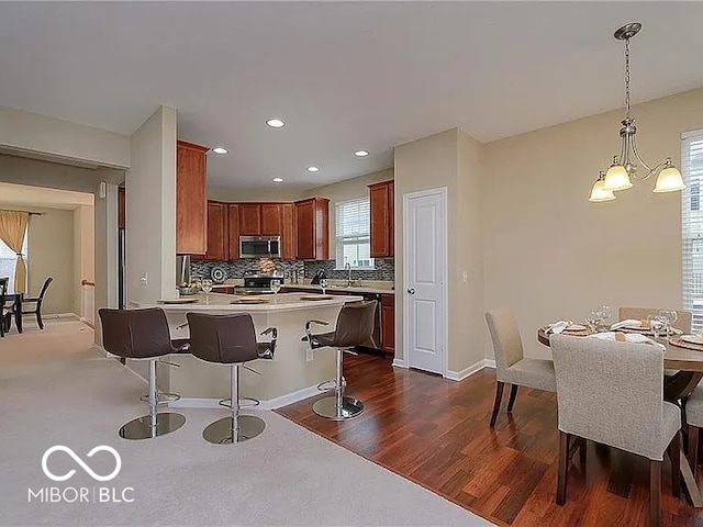 kitchen with dark wood-style floors, light countertops, decorative backsplash, appliances with stainless steel finishes, and a peninsula