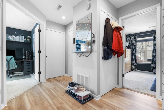 mudroom with wood finished floors, visible vents, and baseboards