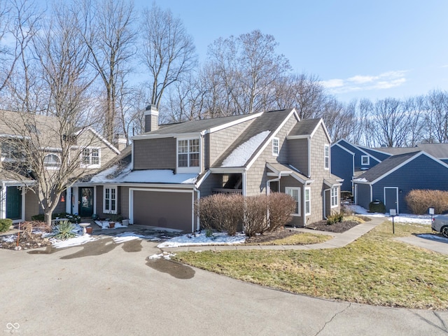 shingle-style home featuring an attached garage, driveway, a residential view, a chimney, and a front yard