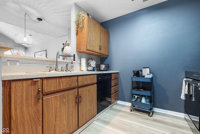 kitchen with decorative light fixtures, light wood finished floors, light countertops, brown cabinetry, and dishwasher