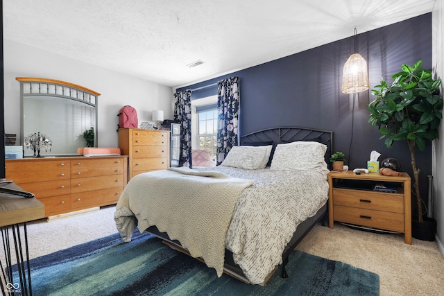 bedroom with carpet floors, visible vents, and a textured ceiling