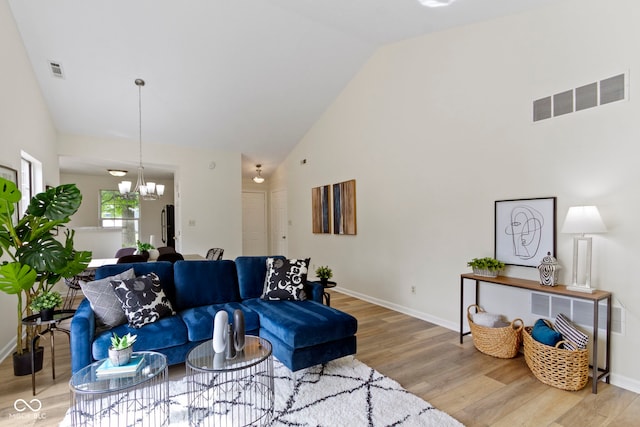 living area featuring high vaulted ceiling, wood finished floors, baseboards, and a chandelier
