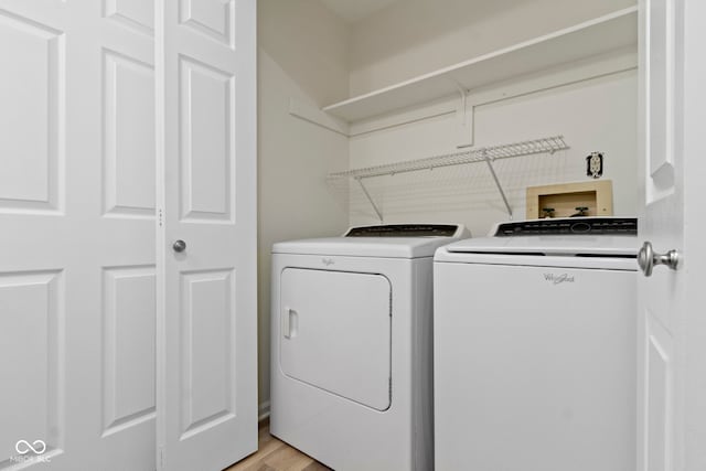 clothes washing area with washer and dryer and light wood-type flooring