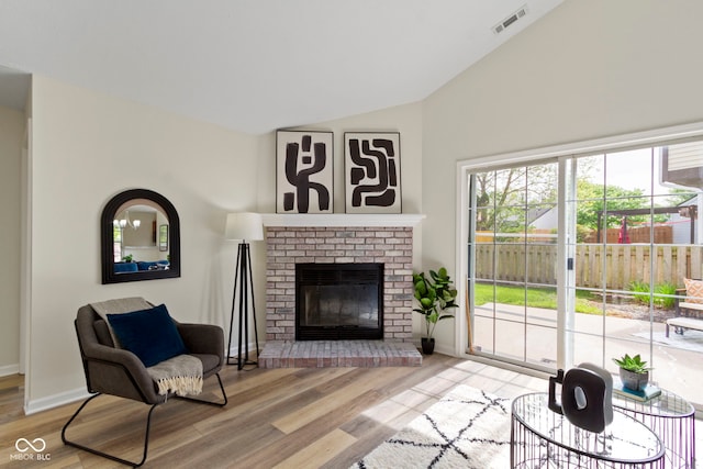 living room featuring lofted ceiling, wood finished floors, a fireplace, and baseboards