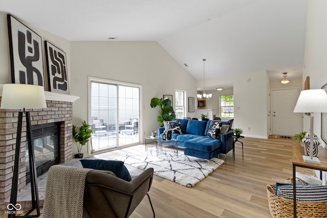 living room with light wood-style flooring, a fireplace, a chandelier, high vaulted ceiling, and baseboards