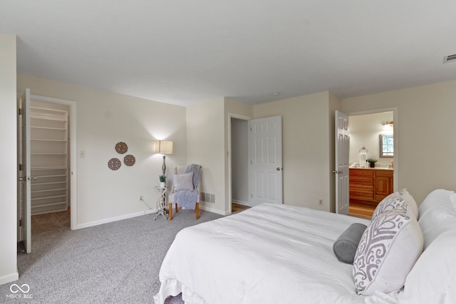 carpeted bedroom with baseboards, ensuite bathroom, and a spacious closet