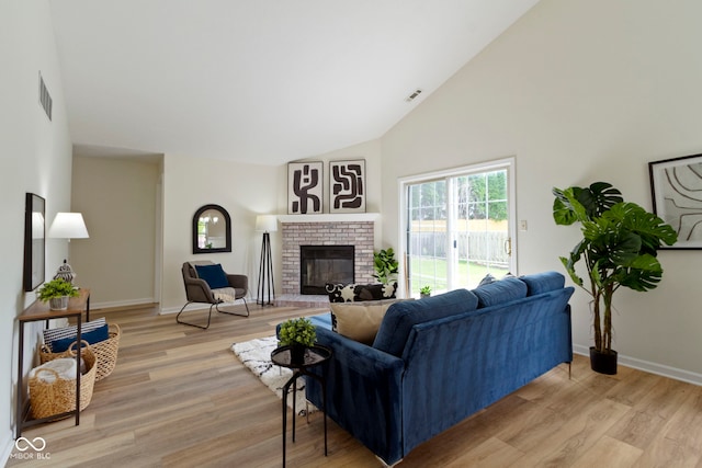 living area featuring a fireplace, light wood finished floors, high vaulted ceiling, and baseboards