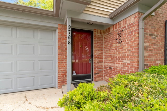 entrance to property with brick siding and a garage