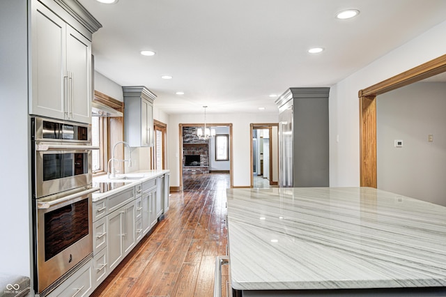 690 N 600 W, Lebanon, IN 46052 - kitchen with double oven, light stone counters, a sink, light wood-type flooring, and gray cabinets