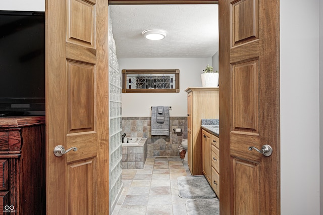 690 N 600 W, Lebanon, IN 46052 - full bath featuring tile walls, toilet, a textured ceiling, vanity, and a bath