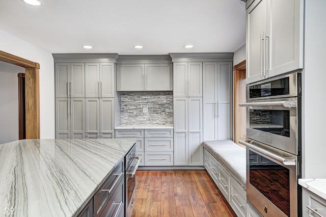 690 N 600 W, Lebanon, IN 46052 - kitchen with decorative backsplash, gray cabinetry, double oven, dark wood-type flooring, and light stone countertops