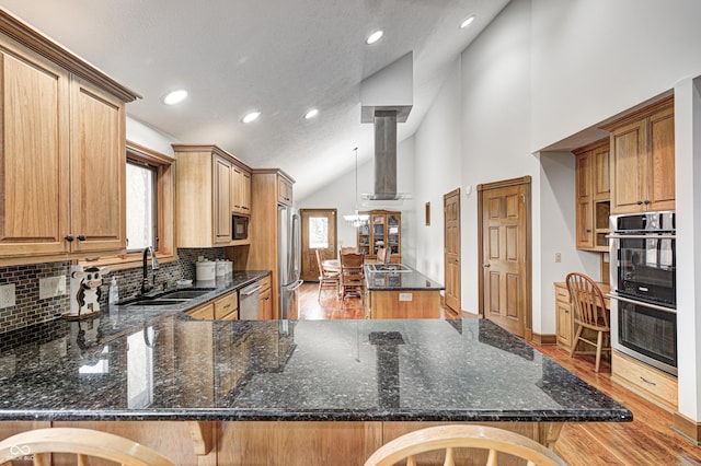 690 N 600 W, Lebanon, IN 46052 - kitchen with light wood-style flooring, appliances with stainless steel finishes, a sink, wall chimney range hood, and a peninsula