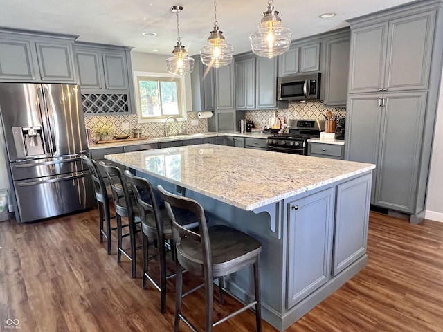 kitchen with dark wood-style floors, stainless steel appliances, a center island, and gray cabinetry