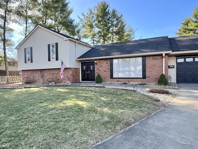 tri-level home featuring brick siding, a shingled roof, a front yard, fence, and a garage